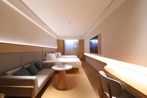 Una habitación de hotel moderna con sofá, cama, escritorio y una silla.