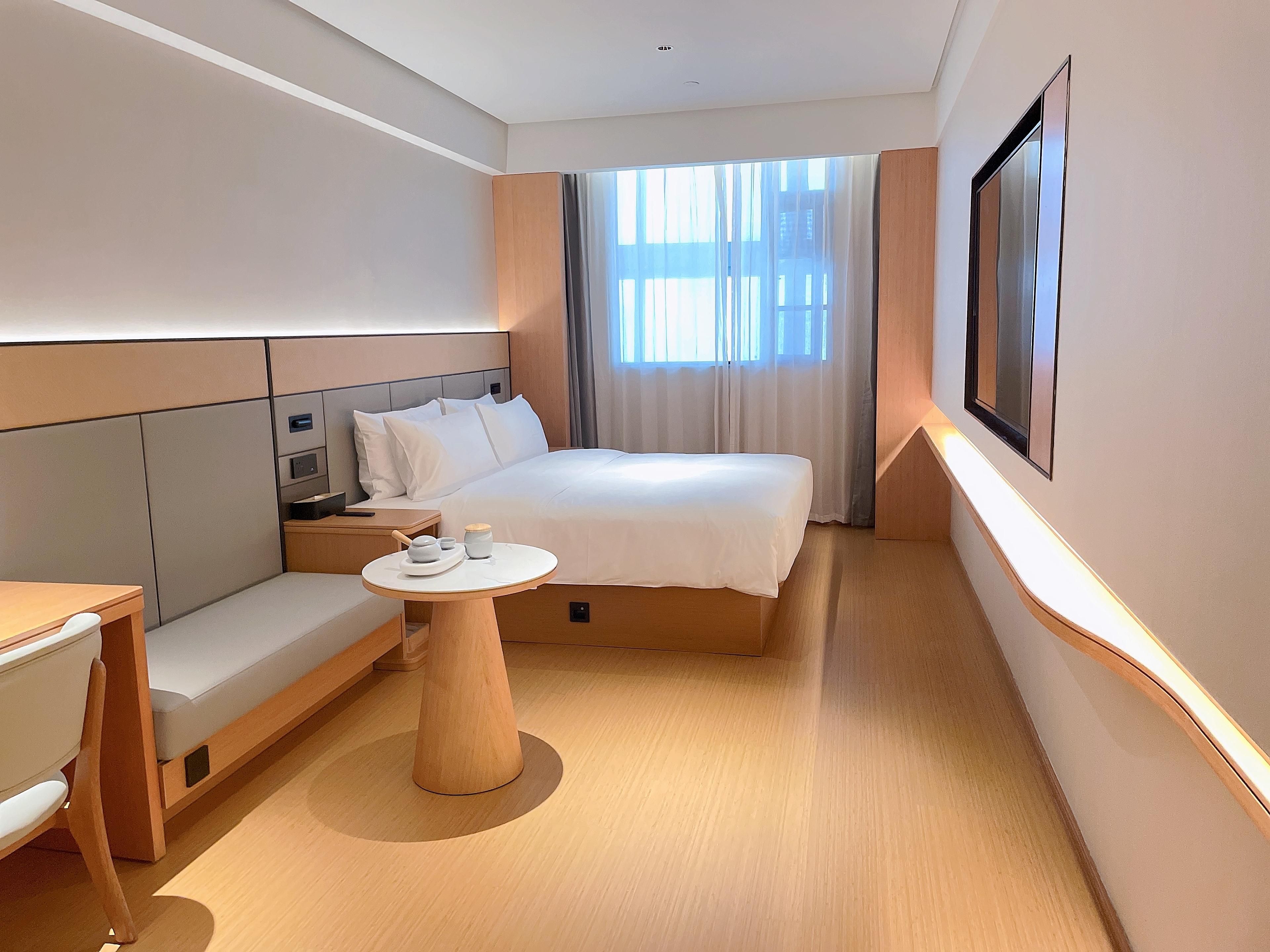 A hotel room with a bed, bedside table, and a small round table with a cup and saucer.