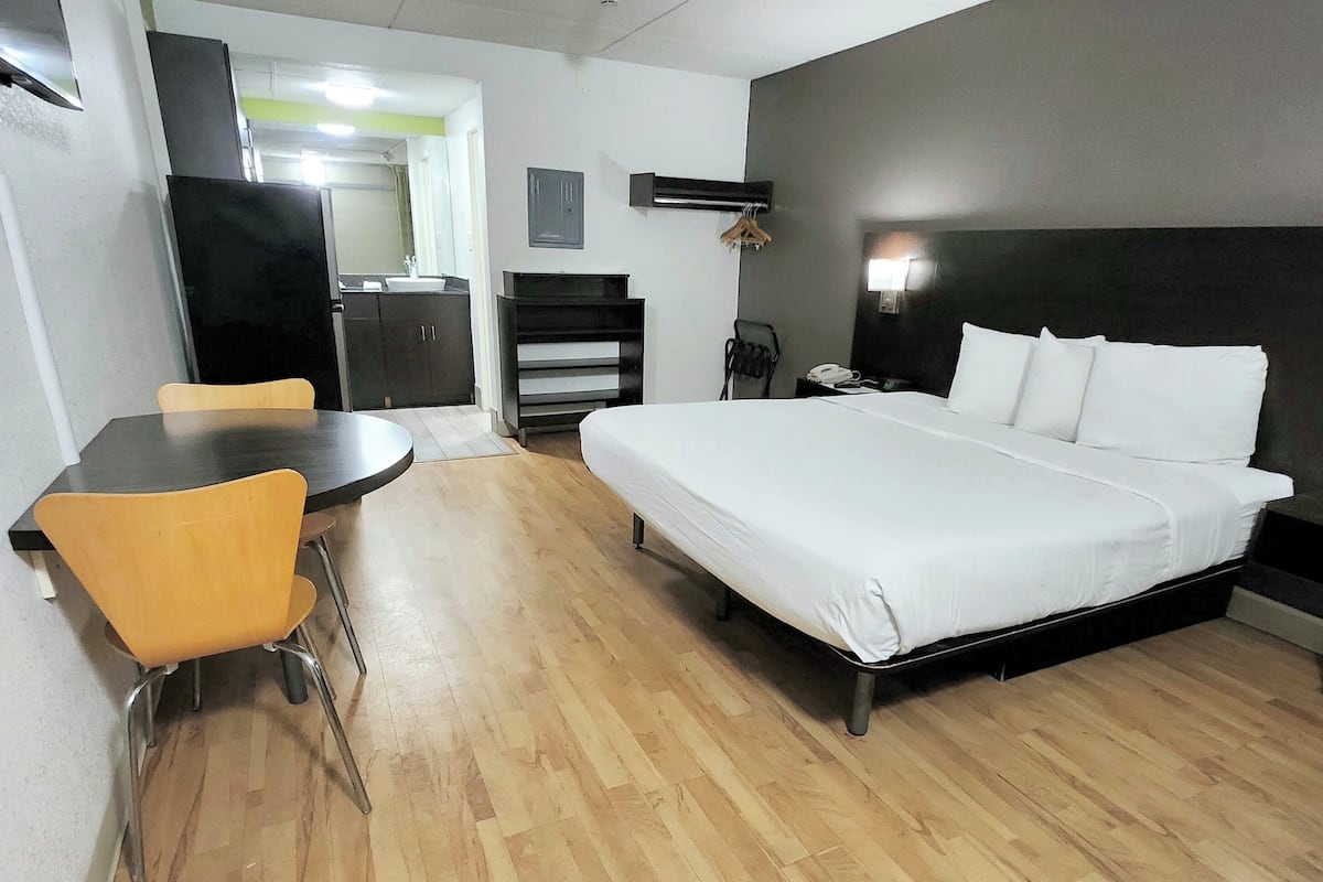 A hotel room with a bed, a desk, a chair, a wardrobe, and a mirror.
