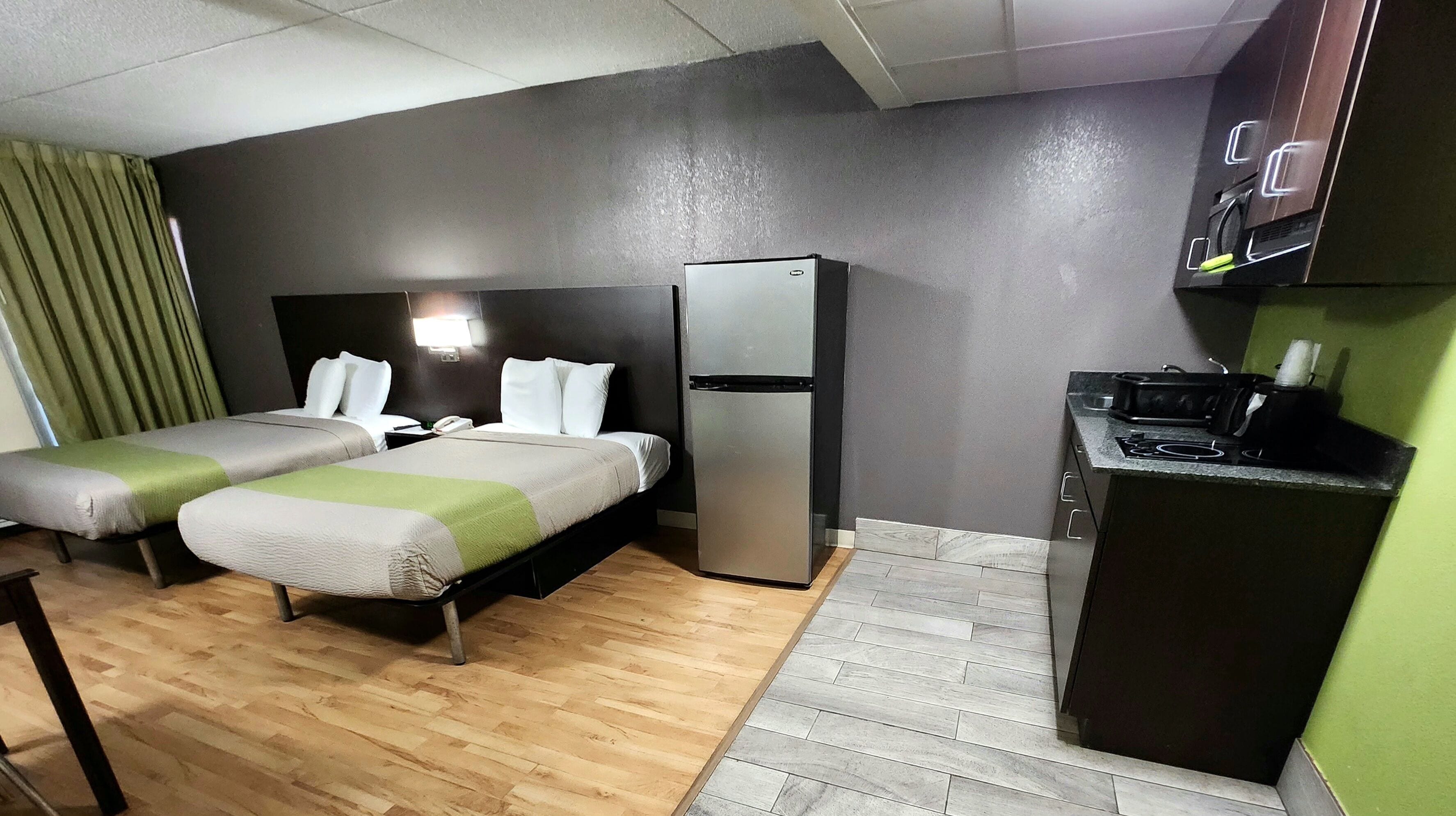 Une chambre d’hôtel avec deux lits, un réfrigérateur, un petit coin cuisine et un plancher en bois.