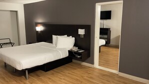 Una camera d'albergo con un letto, un comodino, una lampada e uno specchio.