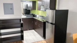 Una cucina compatta con frigorifero, forno a microonde e macchina del caffè.