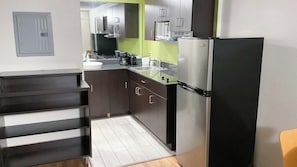 Cocina compacta equipada con refrigerador, microondas y cafetera.