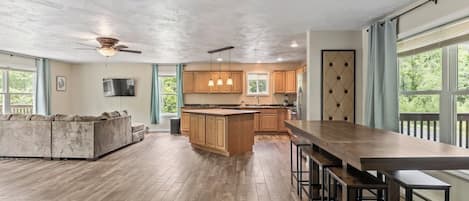 A spacious kitchen with a central island, wooden cabinets, and a large dining area with bar stools.