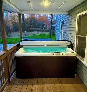 Un jacuzzi en una terraza de madera con vista a un jardín y árboles.