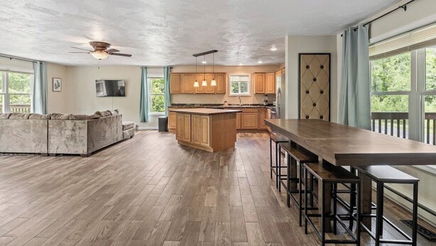 A spacious kitchen with a central island, wooden cabinets, and a large dining table with bar stools. - Spacious Home Sleeps 20! Dogs OK (Lansing)