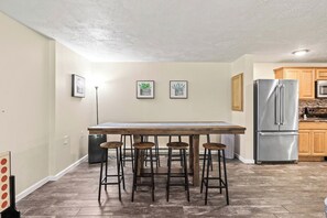 Cocina con una isla central, taburetes de bar, refrigerador de acero inoxidable y armarios de madera.