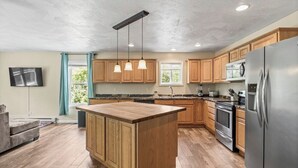 A modern kitchen with wooden cabinets, a central island, stainless steel appliances, and pendant lighting. - Spacious Home Sleeps 20! Dogs OK (Lansing)