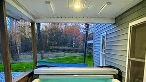 A hot tub on a wooden deck with a view of a yard and trees. - Spacious Home Sleeps 20! Dogs OK (Lansing)