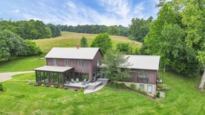 A modern two-story house with a covered patio and a large lawn. - Hillside haven on expansive grounds, heated pool, firepit, bocce court and more! (Logan)