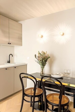 Uma cozinha moderna com bancada branca, uma cadeira preta e um vaso de flores na mesa.