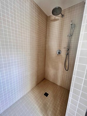 Um pequeno banheiro com azulejos, chuveiro e chuveiro manual.