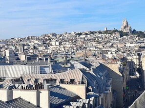 Paisagem urbana com uma catedral imponente ao fundo, vários edifícios e céu claro.
