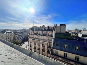 A cityscape with a prominent building featuring a balcony and a clear sky.