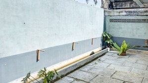 A courtyard with a grey wall, potted plants, and a tiled floor. - Hotel O Sulthan Homestay Syariah 2 (Palembang)