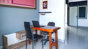 A conference room with a wooden table, two black chairs, a laptop, and a framed picture on the wall. - Hotel O Sulthan Homestay Syariah 2 (Palembang)