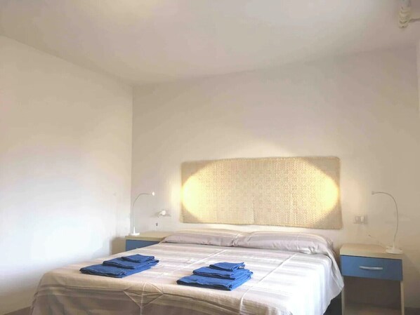 A hotel room with a bed, two bedside tables, and a headboard.
