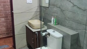 A bathroom with a toilet, sink, and mirror. - Kabini Earthern Cottages Lakeside Farmstay
 (Holehundi)