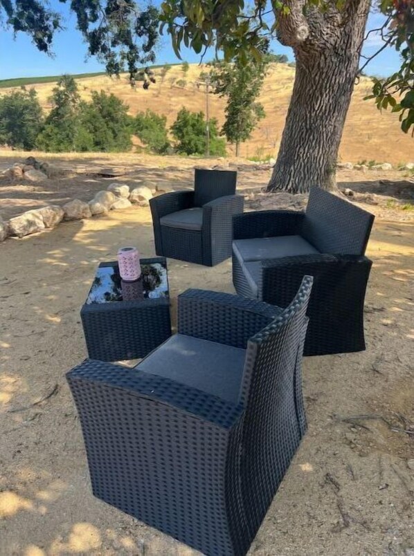 Outdoor wicker furniture with cushions, a small table, and a decorative item on a concrete surface.