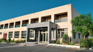 A modern hotel with a prominent entrance, multiple windows, and a landscaped area with plants. - Hôtel Debrazza (Ouled Tayeb)