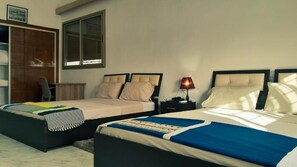 A hotel room with two beds, a wardrobe, a desk, and a window.