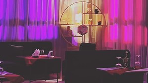 A room with a black sofa, a round side table, and a small table with a lamp. - Hôtel Debrazza (Ouled Tayeb)