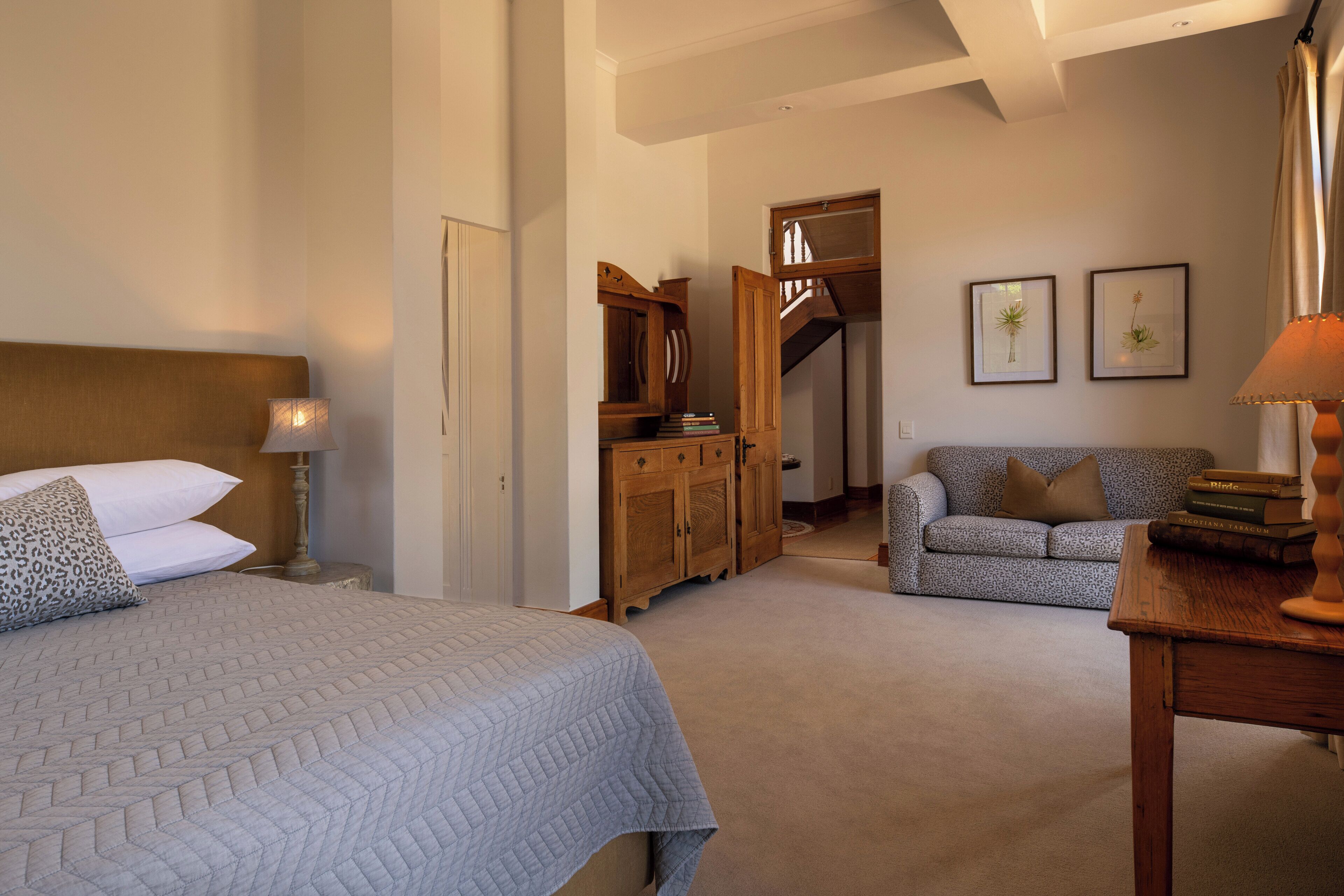 Une chambre à coucher avec un lit, une table de chevet, une commode, un canapé et une table avec des livres.