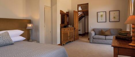 Une chambre à coucher avec un lit, une table de chevet, une commode, un canapé et une table avec des livres.