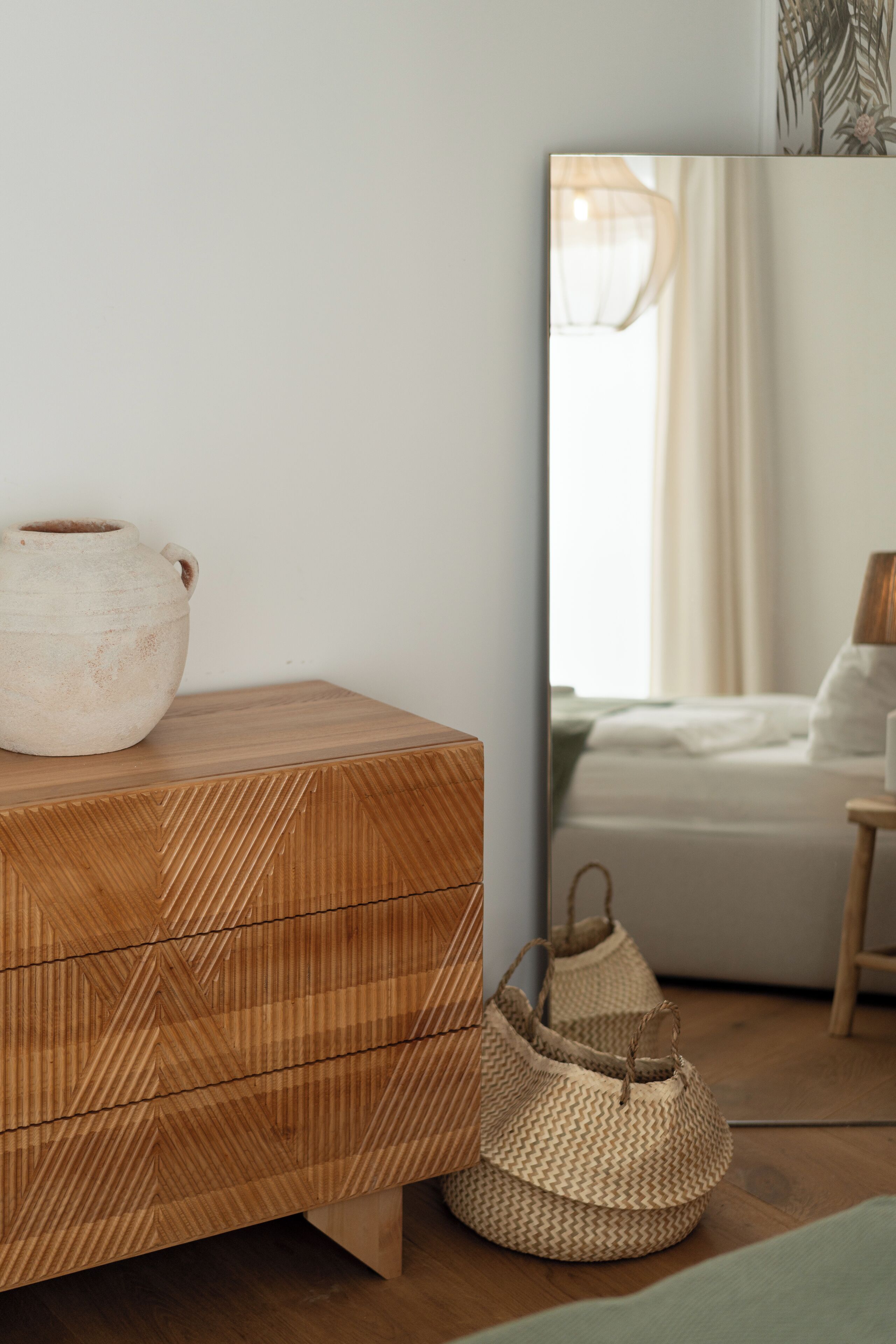 Un aparador de madera con una cesta tejida y un jarrón grande.