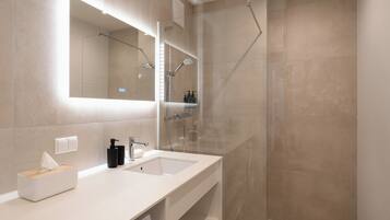 A modern bathroom with a large mirror, a sink, and a shower enclosure.
