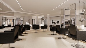 Un salón moderno con varias sillas de peluquería negras, un mostrador de recepción central y una amplia pared de espejos.