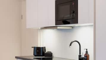 A modern kitchen with white cabinets, a built-in microwave, a stainless steel sink, and an oven.