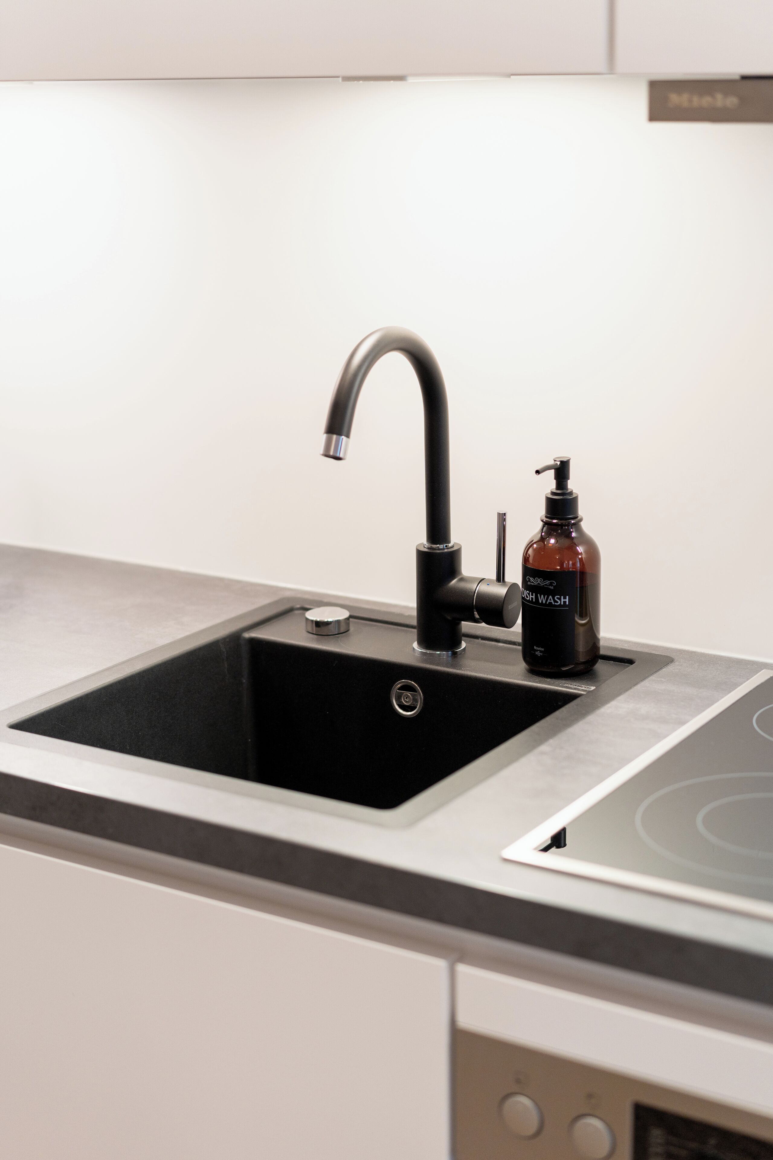 A kitchen sink with a modern faucet and a soap dispenser.