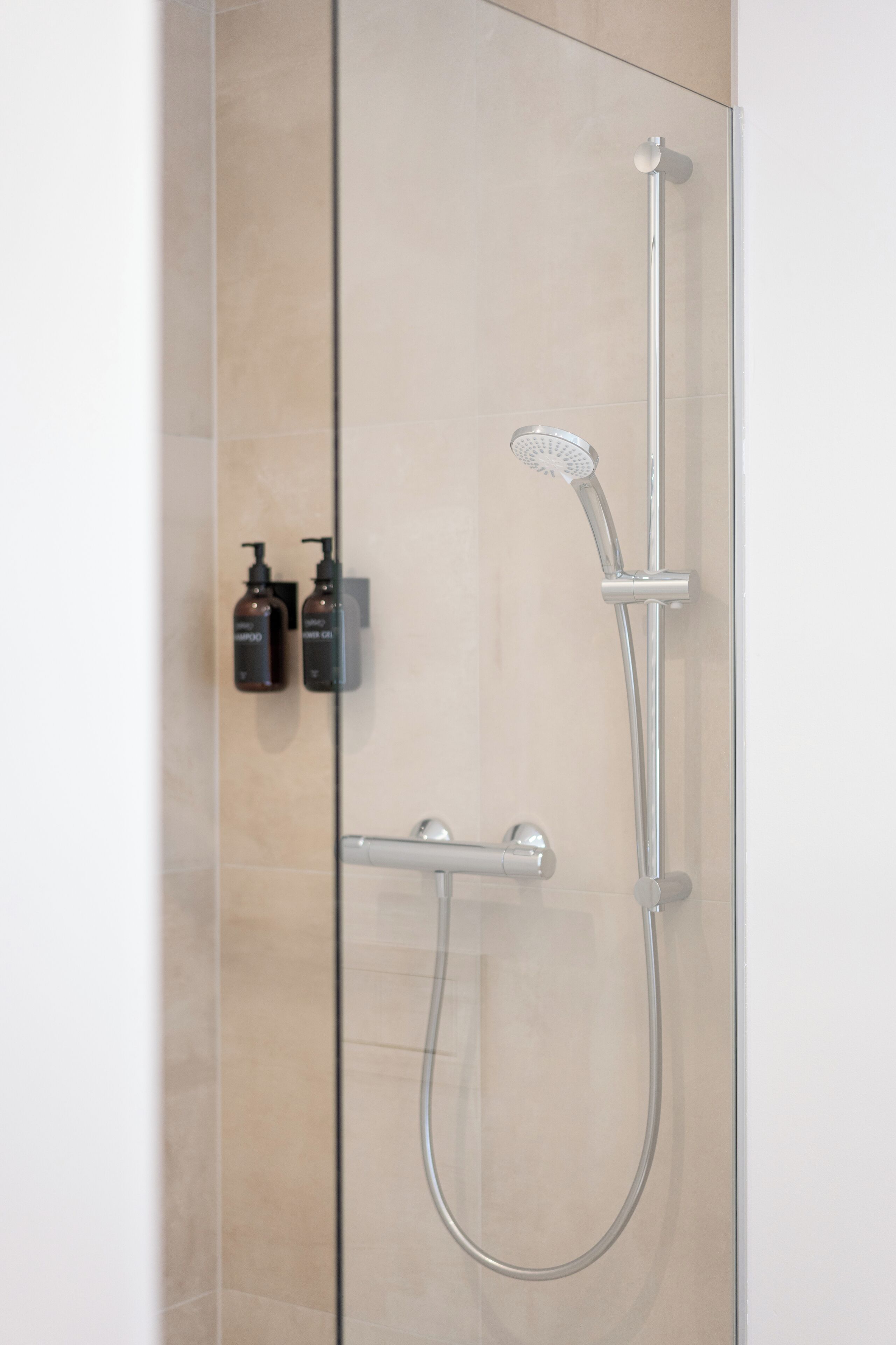 A modern shower with a handheld showerhead and a wall-mounted control panel.