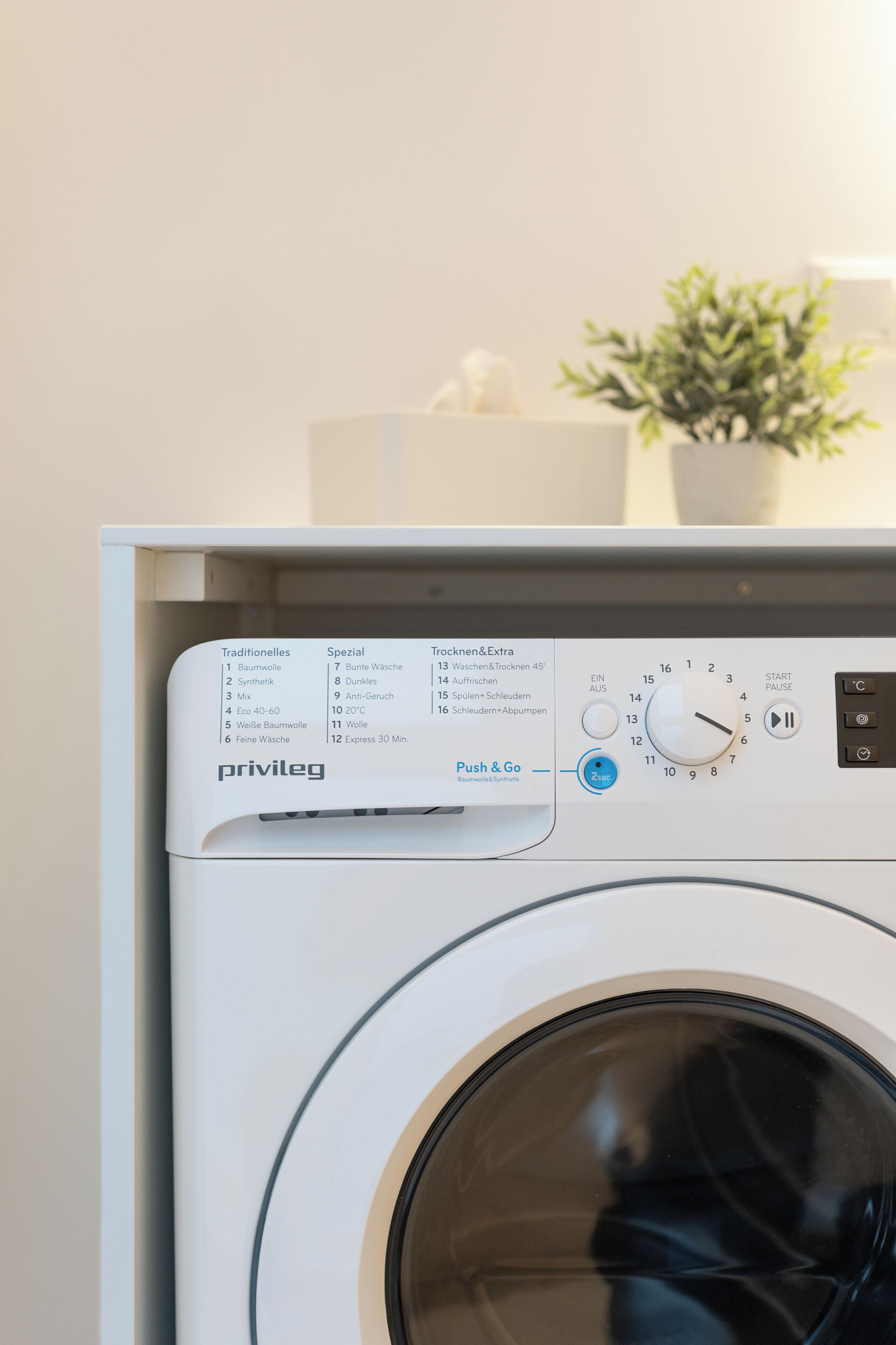 Un lave-linge à chargement frontal doté d’un panneau de commande affichant différents programmes de lavage et d’un bouton « Appuyer et démarrer ».
