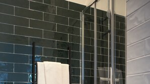 A bathroom with a glass shower enclosure, a white toilet, and a towel rack with folded towels. - Succeed Campo Pequeno Suites (Lisbon)