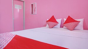 Una habitación con pared rosa, puerta blanca y cama con ropa de cama roja y blanca.