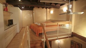Une chambre avec un lit superposé, un bureau avec un ordinateur, une chaise et un ventilateur de plafond.