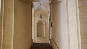 Un escalier en pierre, doté d’une rampe, mène à une porte en arc de cercle située en haut.