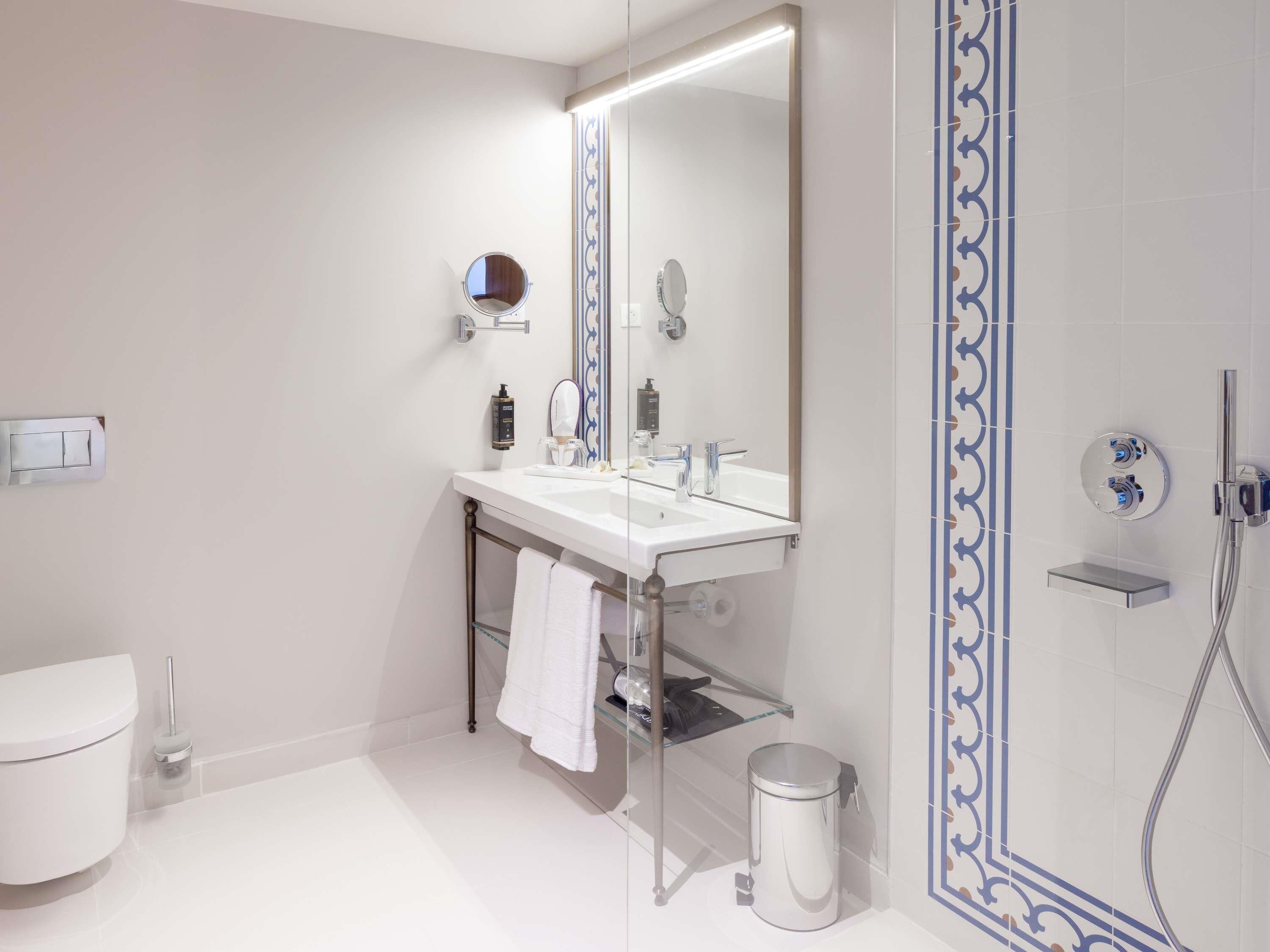 A modern bathroom with a white sink, mirror, and shower.