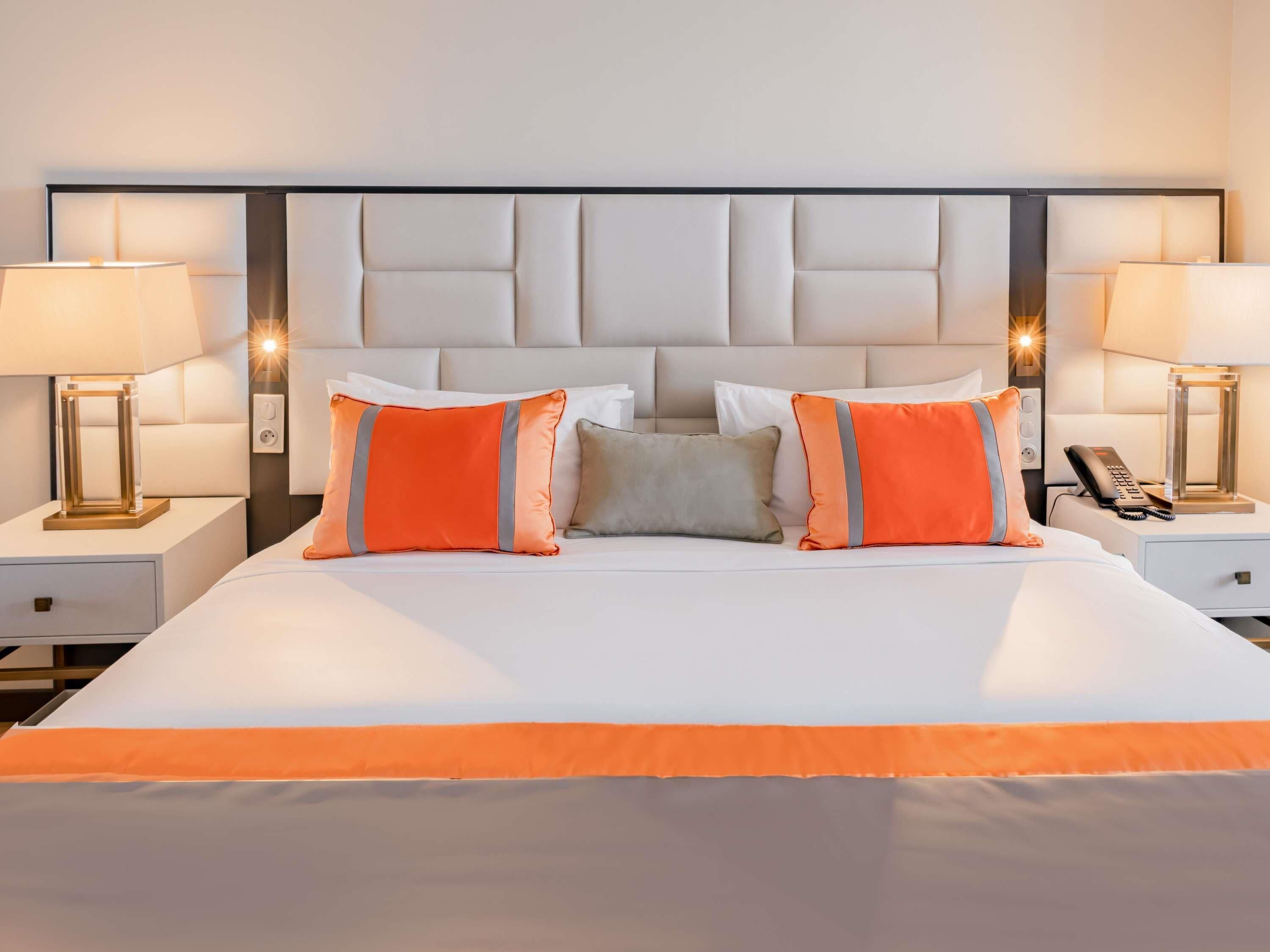 Habitación de hotel con una cama grande, dos mesitas de noche, un teléfono y una lámpara.