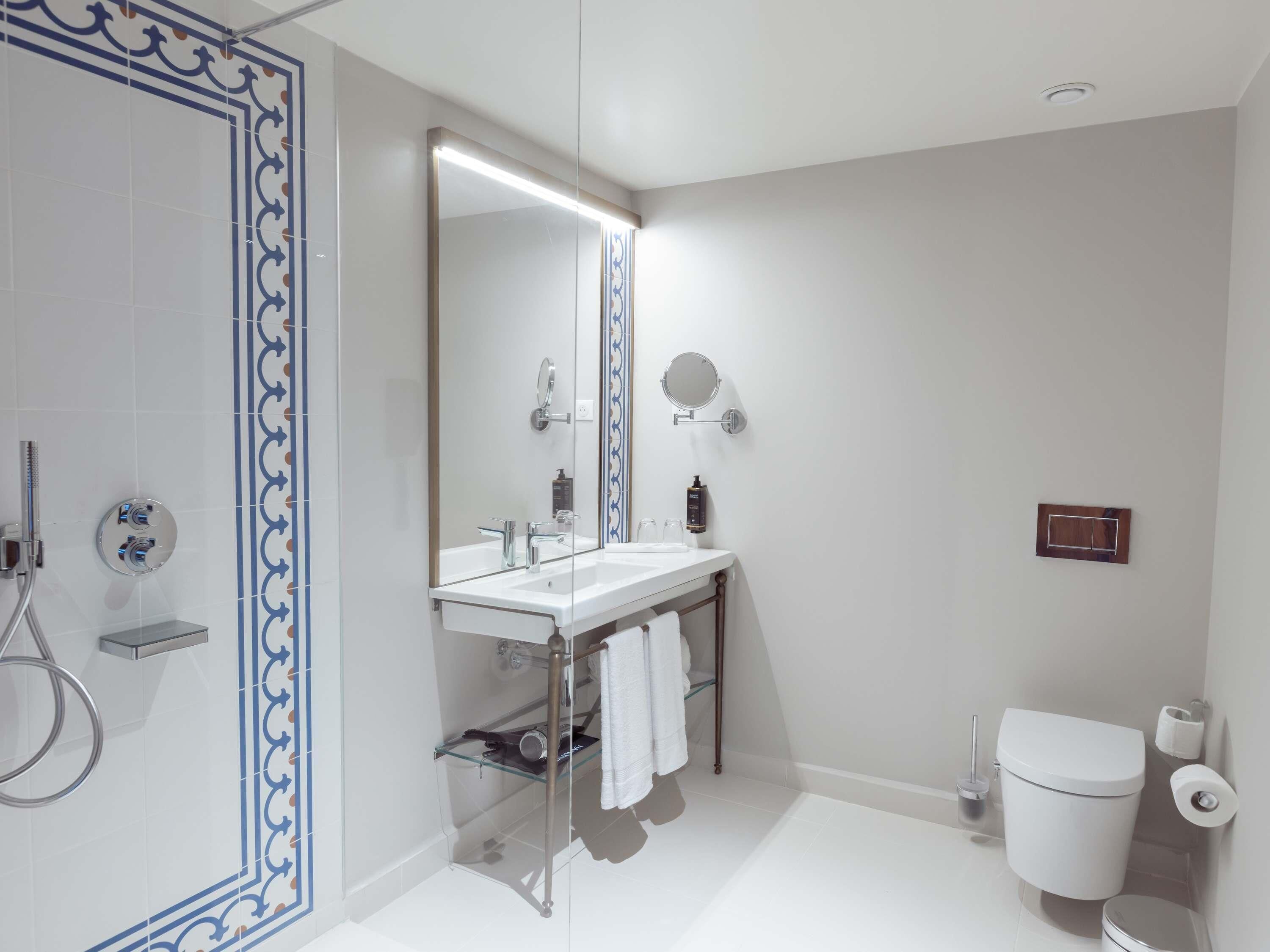 Un baño moderno con cabina de ducha de vidrio, un lavabo blanco con espejo y un inodoro.