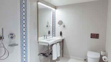 Un baño moderno con cabina de ducha de vidrio, un lavabo blanco con espejo y un inodoro.