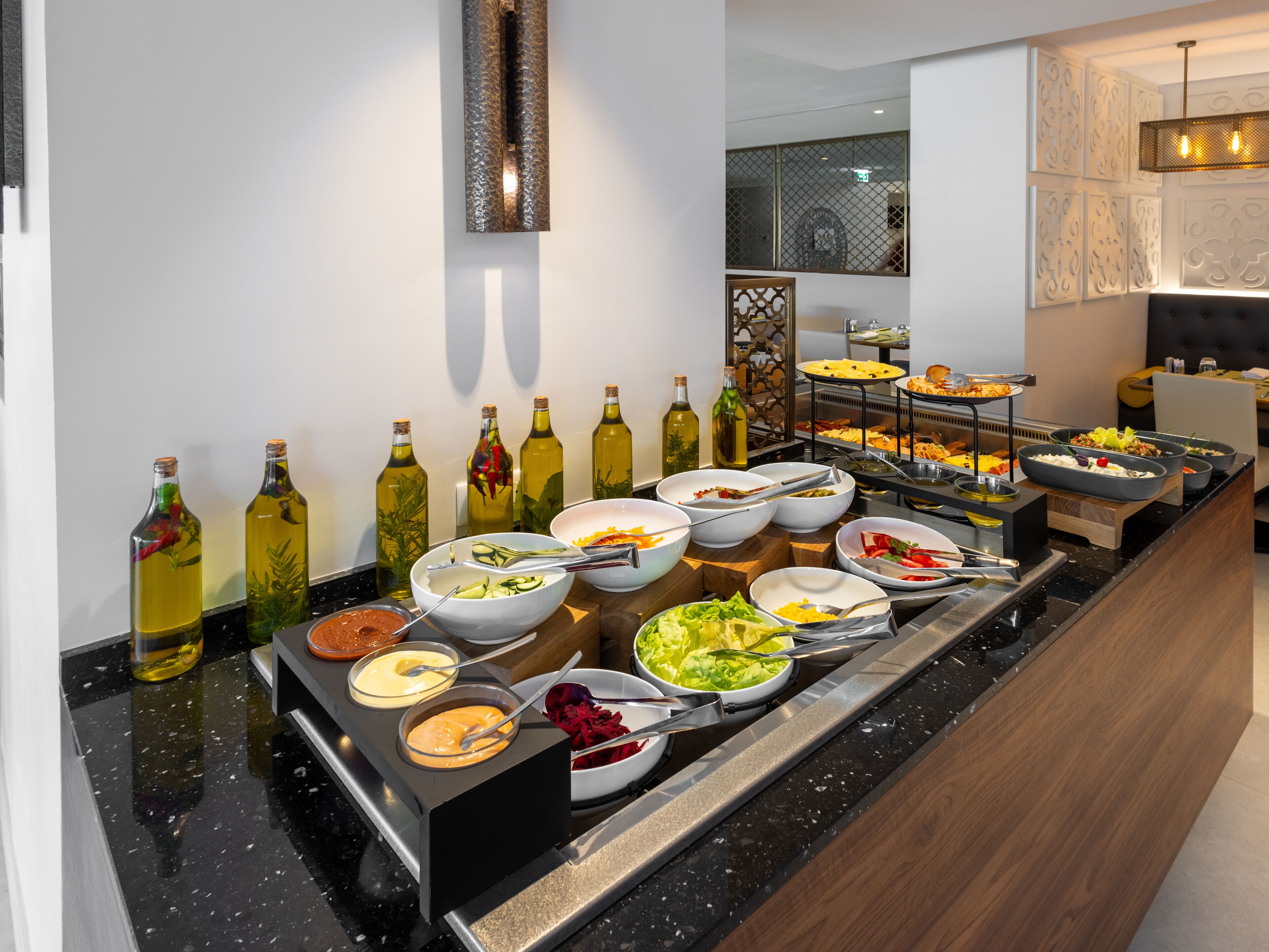 Un buffet proposant une variété de plats et d’accompagnements, notamment des salades, des sauces et un assortiment de fromages.