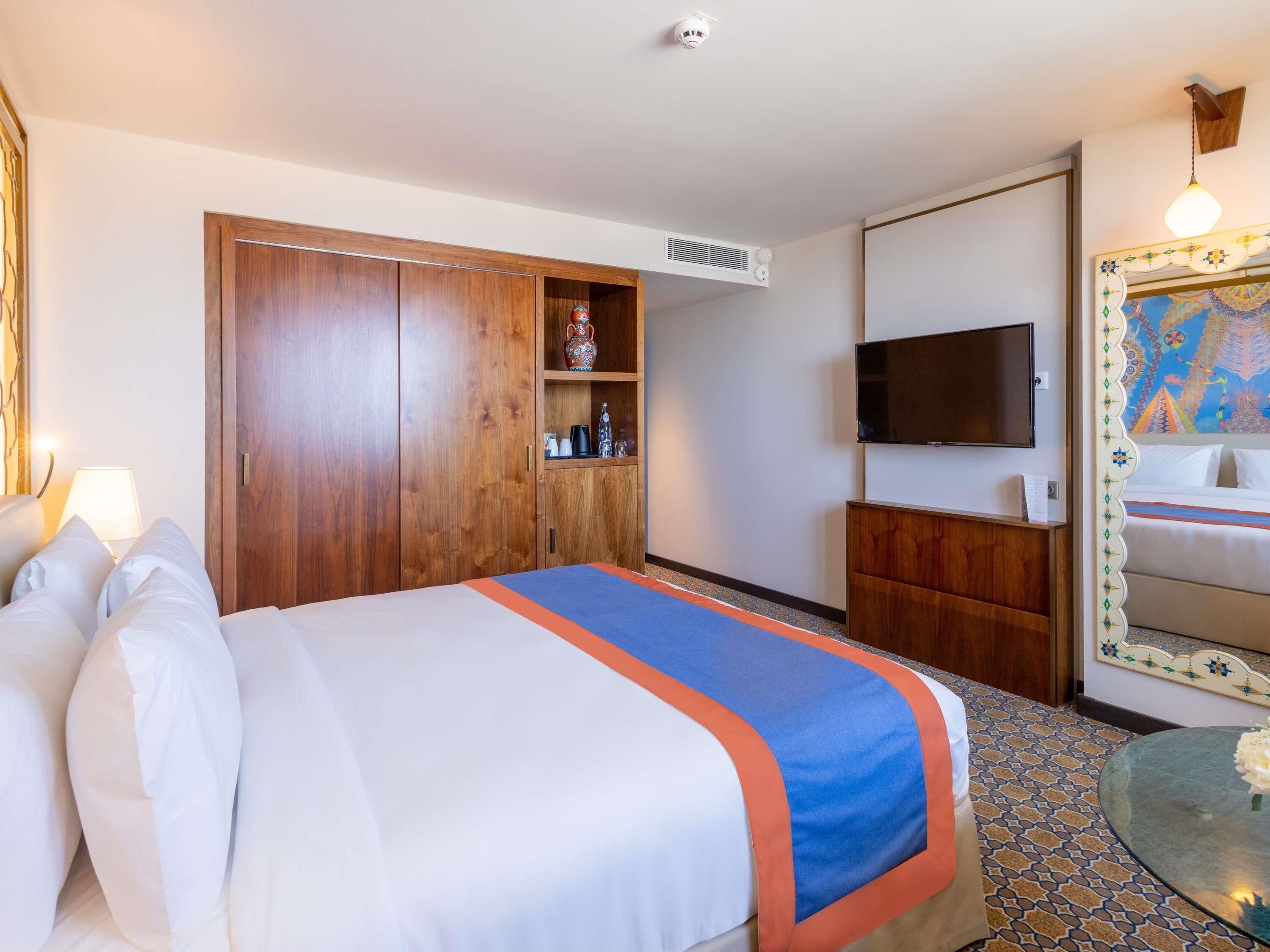 Hotelkamer met een bed, kledingkast, televisie en een badkamer met spiegel en wastafel.