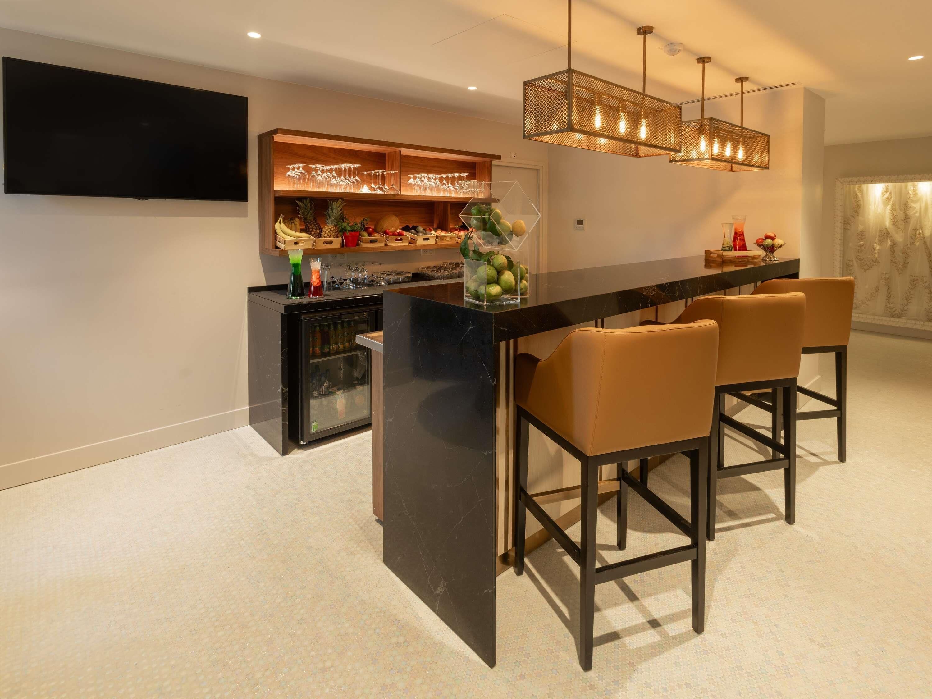 Eine moderne Küche mit schwarzem Marmor-Arbeitsplatz, integriertem Weinkühler und einer Bar mit Barhocker.