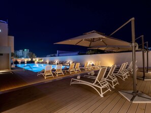 Una piscina al aire libre, sombrillas, sillones reclinables de piscina