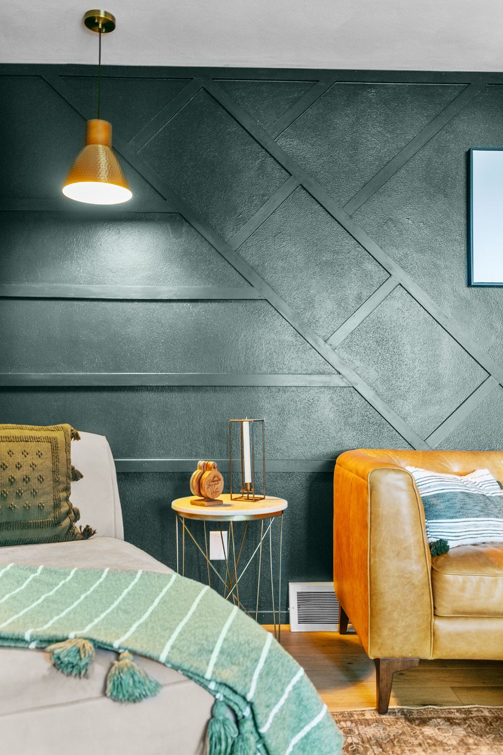 Een moderne slaapkamer met een bed, een nachtkastje, een lamp en een leren bank.