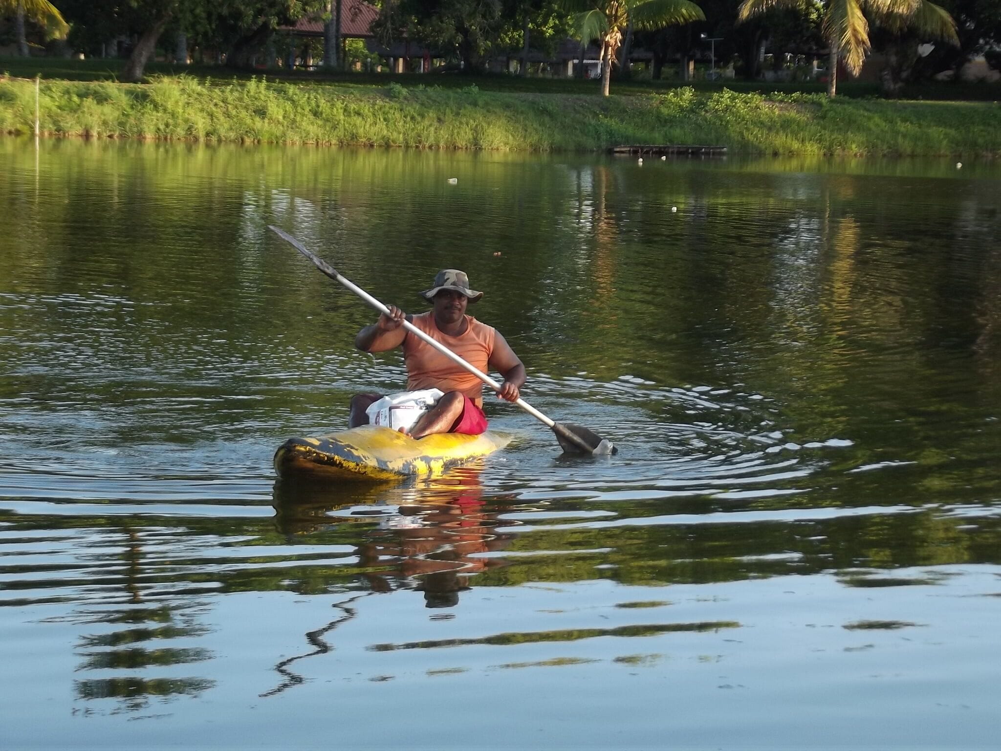 Una persona rema en kayak amarillo sobre aguas tranquilas.