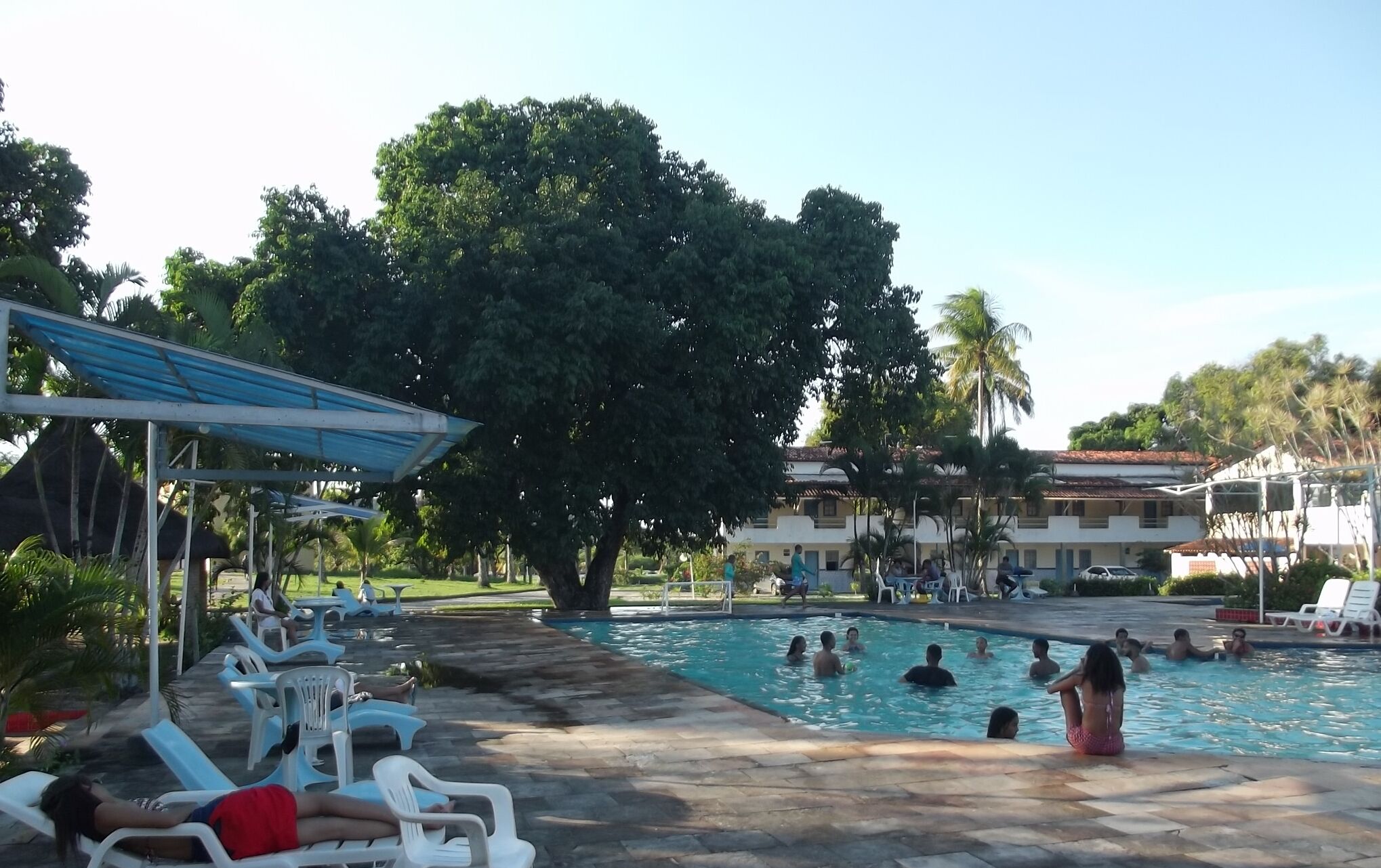 A swimming pool area with lounge chairs and a covered seating area.